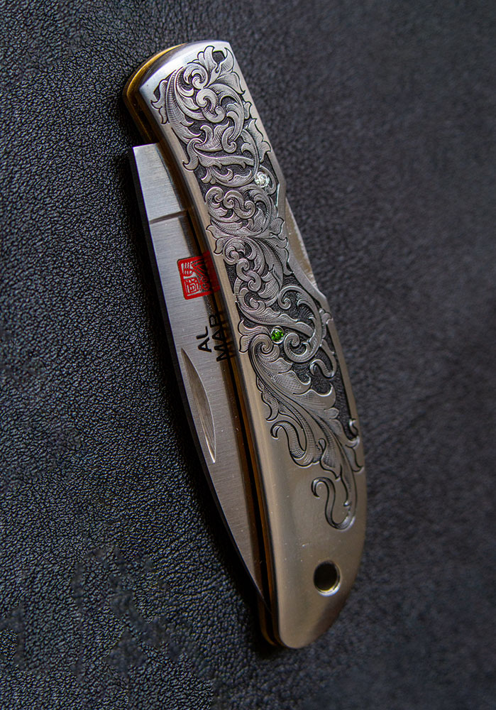 a pocket knife with intricate hand engraved patterns on the handle